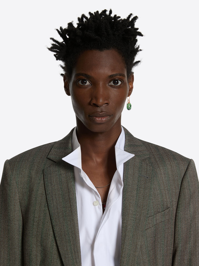 Person wearing a gray blazer over a white shirt with a plain background