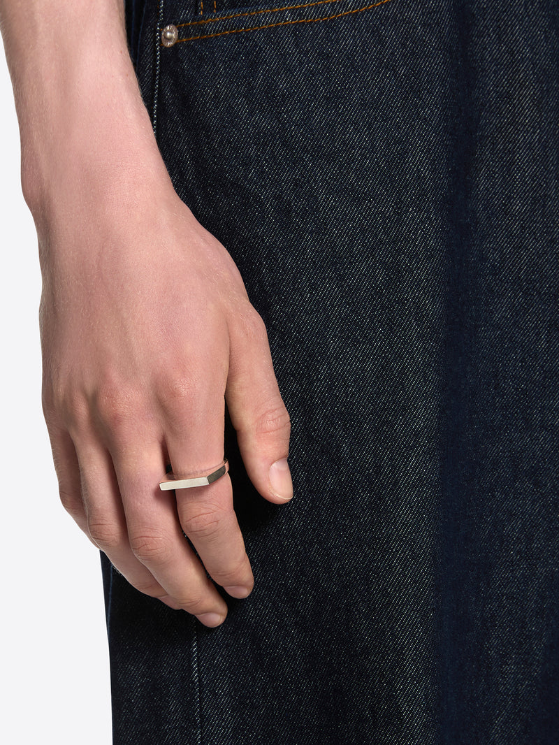 Close-up of a hand wearing a gold ring on a plain background