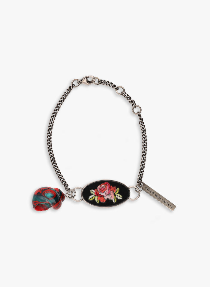 Bracelet with floral charm and tag on a white background