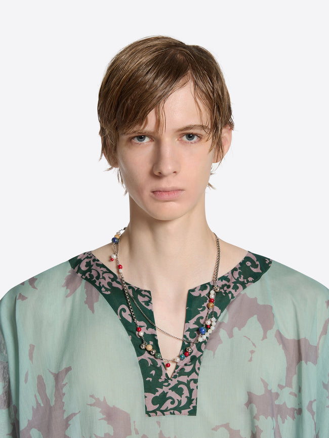 Person wearing a light green blouse with a floral neckline against a white background