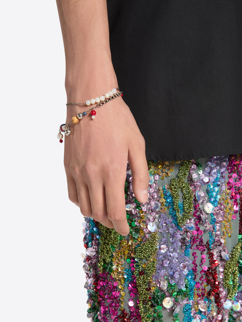 Hand holding a colorful beaded clutch with a plain background