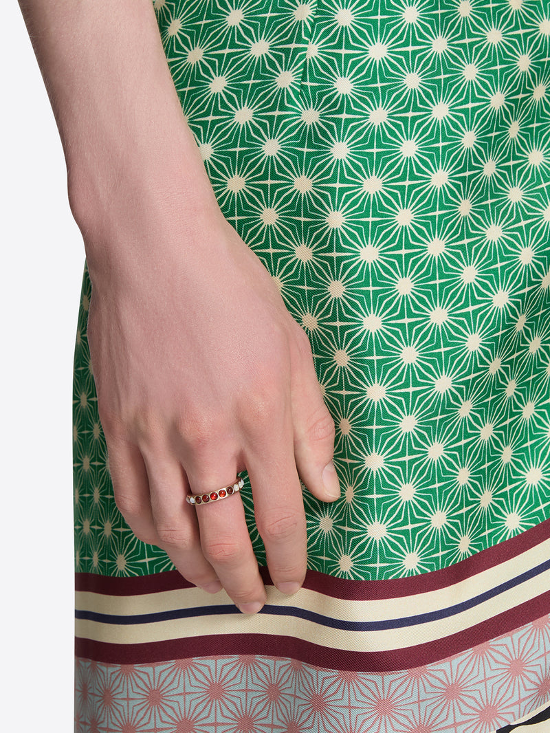 Close-up of a hand wearing a ring on a green patterned fabric background