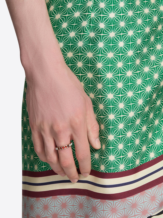 Close-up of a hand wearing a ring on a green patterned fabric background