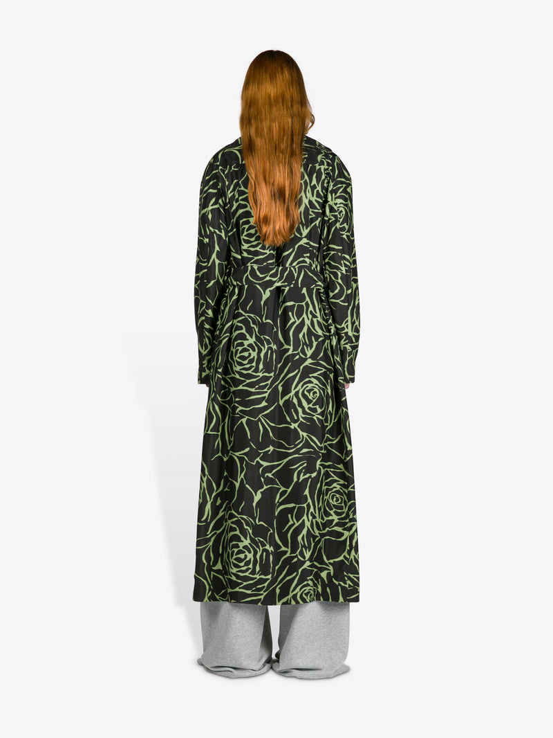 Person wearing a long, dark green floral patterned coat on a white background - Dries Van Noten