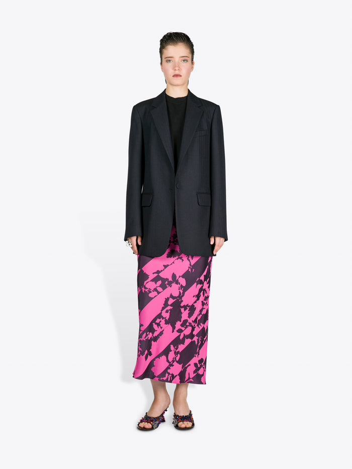 Woman wearing a black blazer and pink and black patterned skirt on a white background - Dries Van Noten
