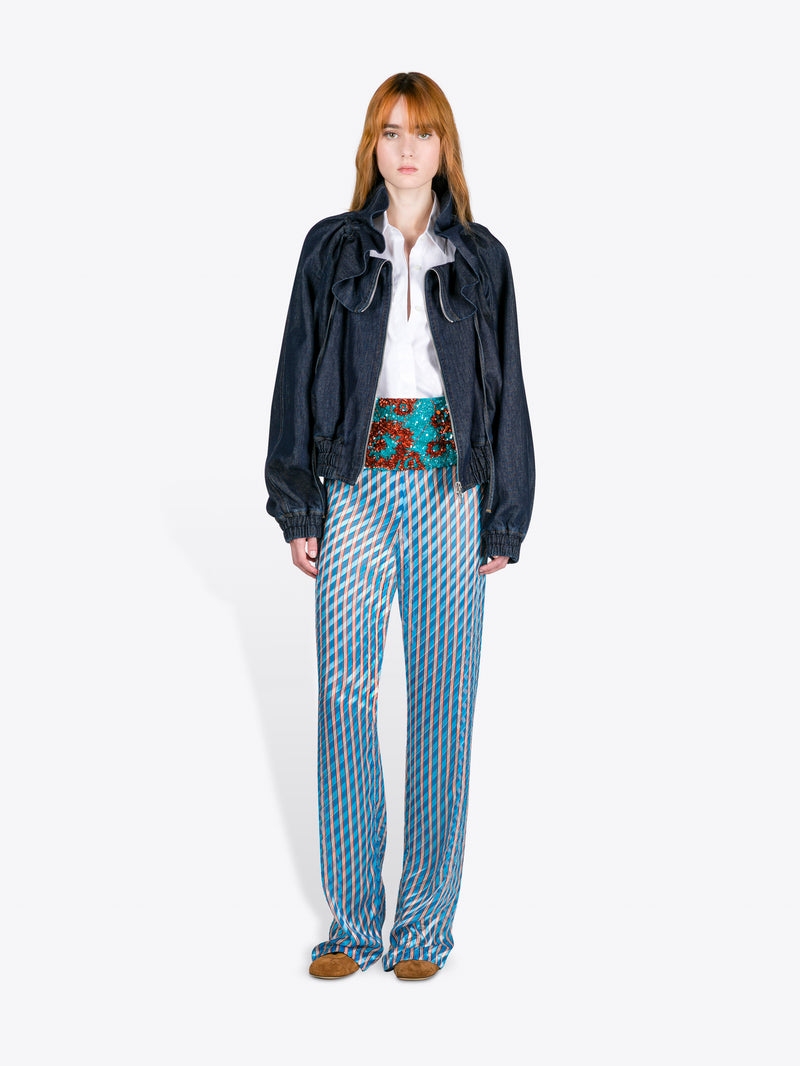 Person wearing a dark jacket, white shirt, and patterned pants on a white background