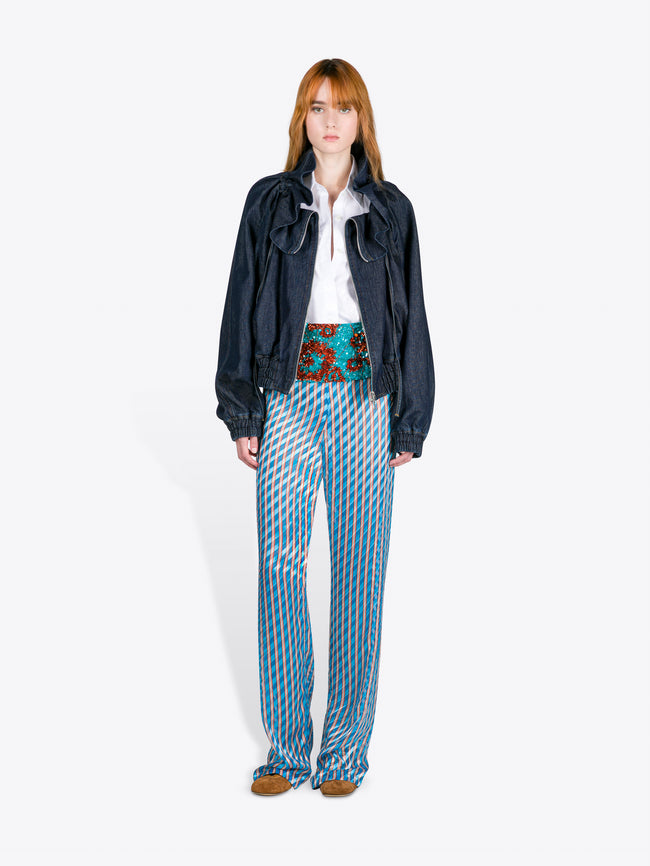 Person wearing a dark jacket, white shirt, and patterned pants on a white background