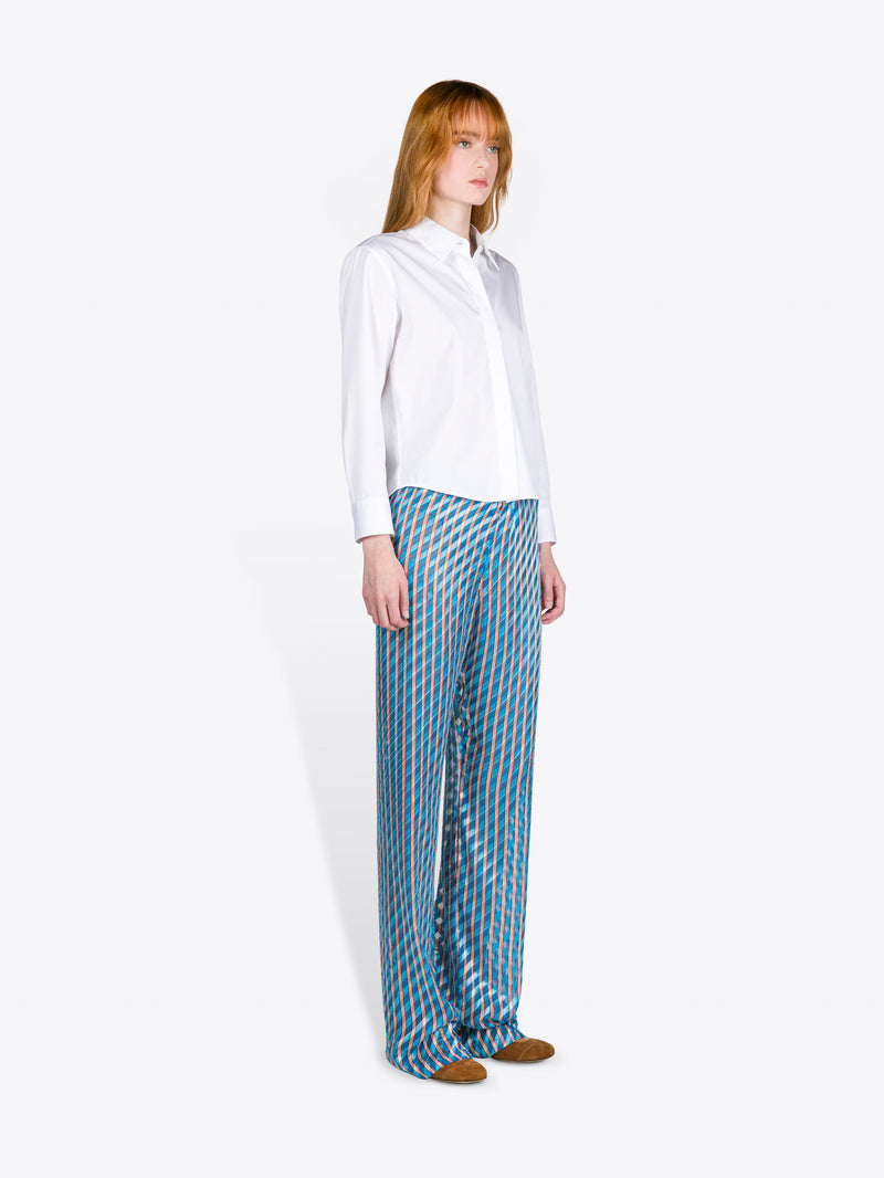 Woman wearing a white blouse and blue patterned pants on a white background