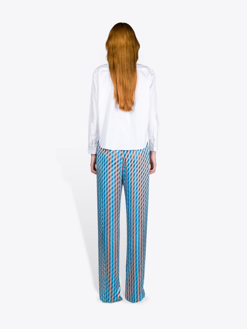 Person wearing a white shirt and blue patterned pants on a white background
