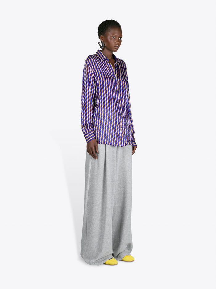 Woman wearing a purple checkered shirt and gray pants on a white background