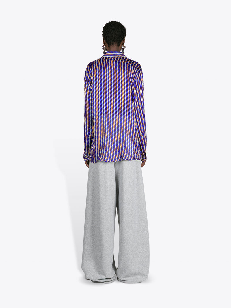 Person wearing a purple checkered shirt and gray pants on a white background