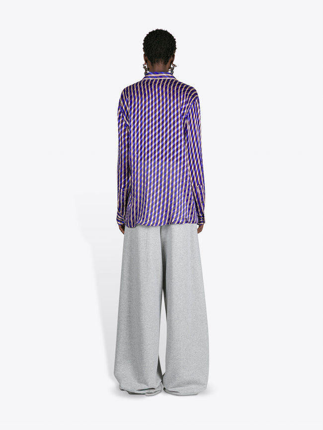 Person wearing a purple checkered shirt and gray pants on a white background