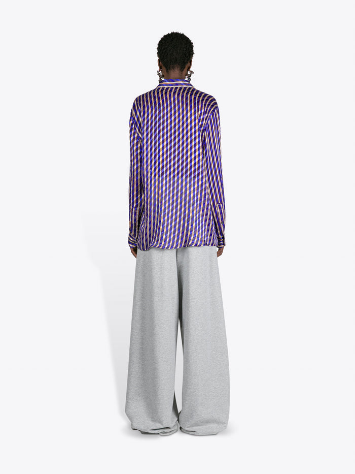 Person wearing a purple checkered shirt and gray pants on a white background
