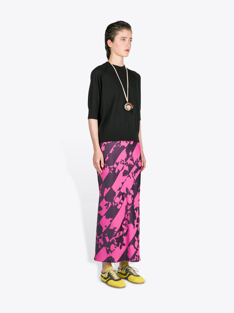 Model wearing a black top and pink floral skirt on a white background