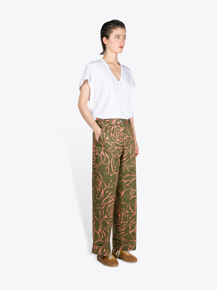 Woman wearing a white top and green patterned pants on a white background