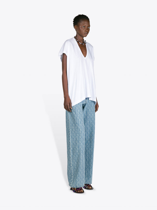 Woman wearing a white top and blue patterned pants on a white background