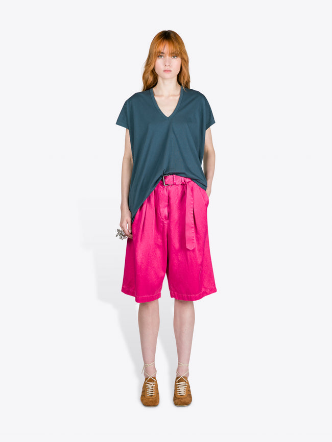 Person wearing a teal top and pink shorts on a white background