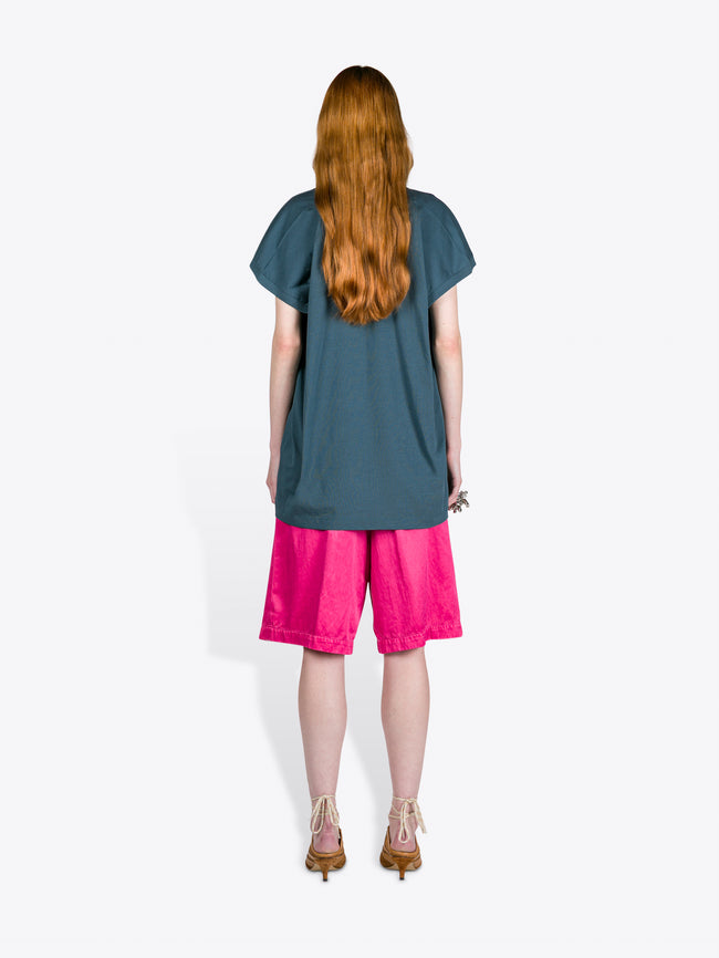 Person wearing a teal top and pink shorts on a white background
