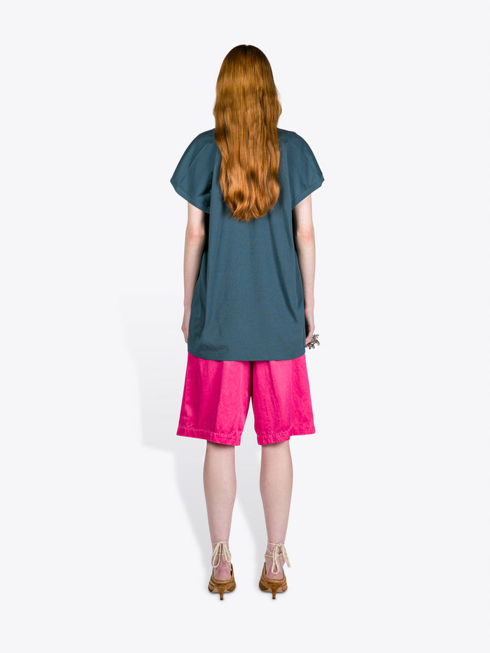 Person wearing a teal top and pink shorts on a white background