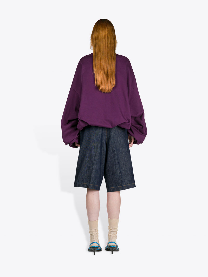 Person wearing a purple shirt and dark shorts from behind on a white background