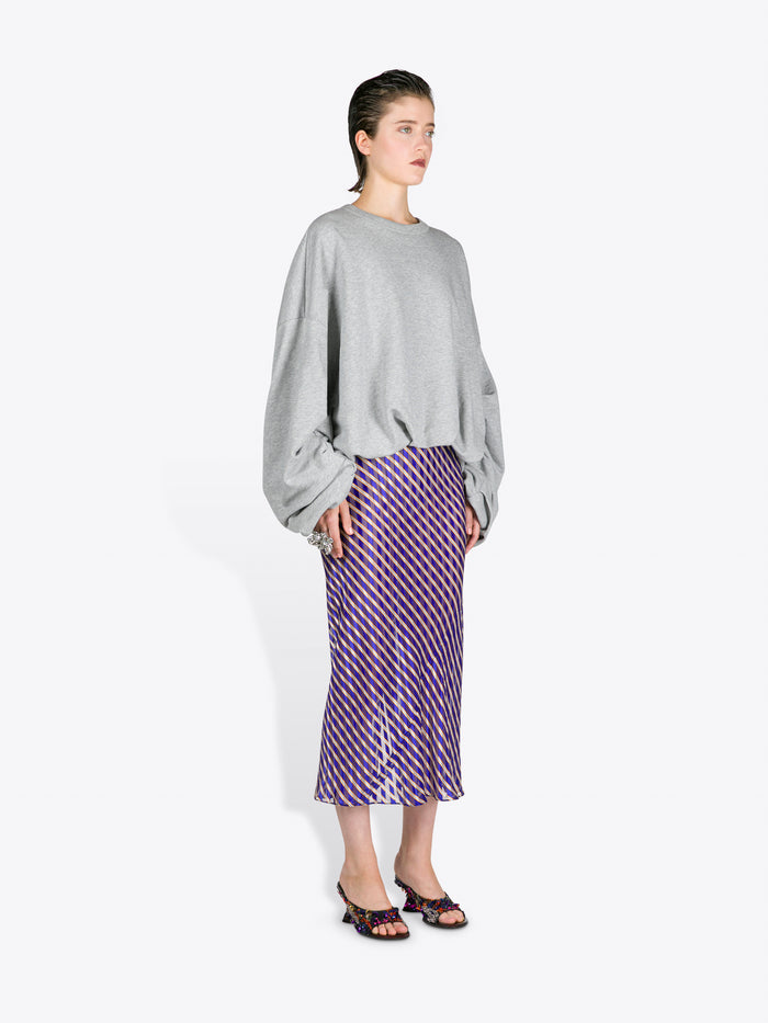 Person wearing a gray sweater and purple striped skirt on a white background