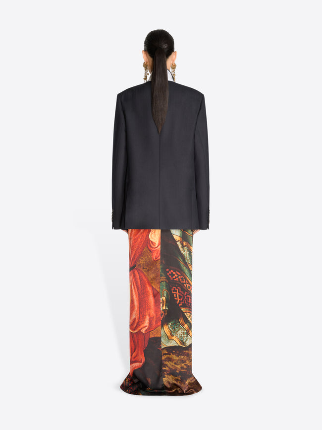 Back view of a model wearing a black double-breasted blazer over a long, wide-leg skirt with an intricate multicolor paisley and floral print.