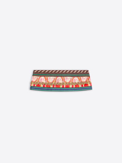 A close-up of a patterned fabric band, likely a belt or waist trim, featuring a red and gold paisley design with a brown geometric border on a light gray background.