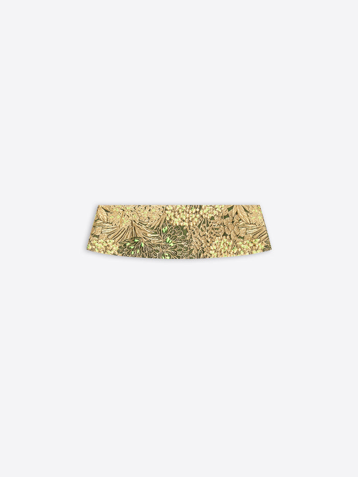 A gold patterned waistband on a light gray background 