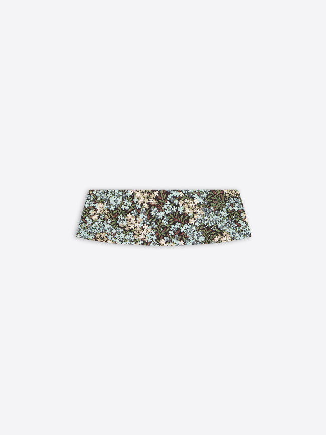 A wide, structured pleated waist band with a dense floral pattern in muted green, beige, and light blue, shown against a light gray background.