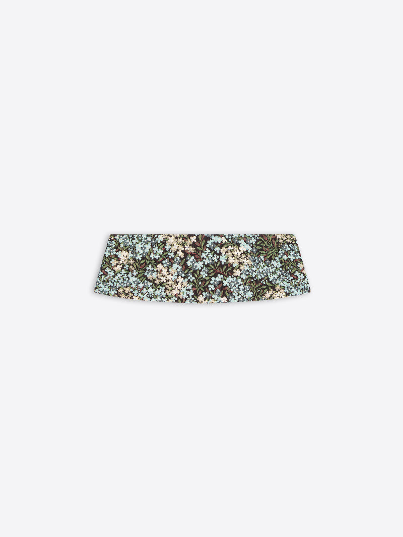 A wide, structured pleated waist band with a dense floral pattern in muted green, beige, and light blue, shown against a light gray background.