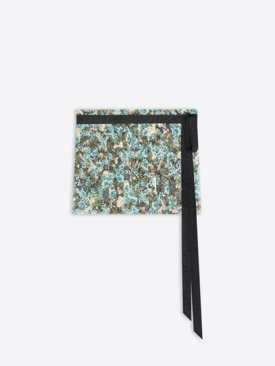 A skirt with a dense floral pattern in shades of blue, green, and beige, accented by a black horizontal band and a long black ribbon tie.