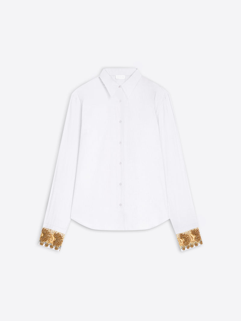 A white long-sleeve button-up shirt with ornate gold sequined cuff details, displayed flat against a light gray background.