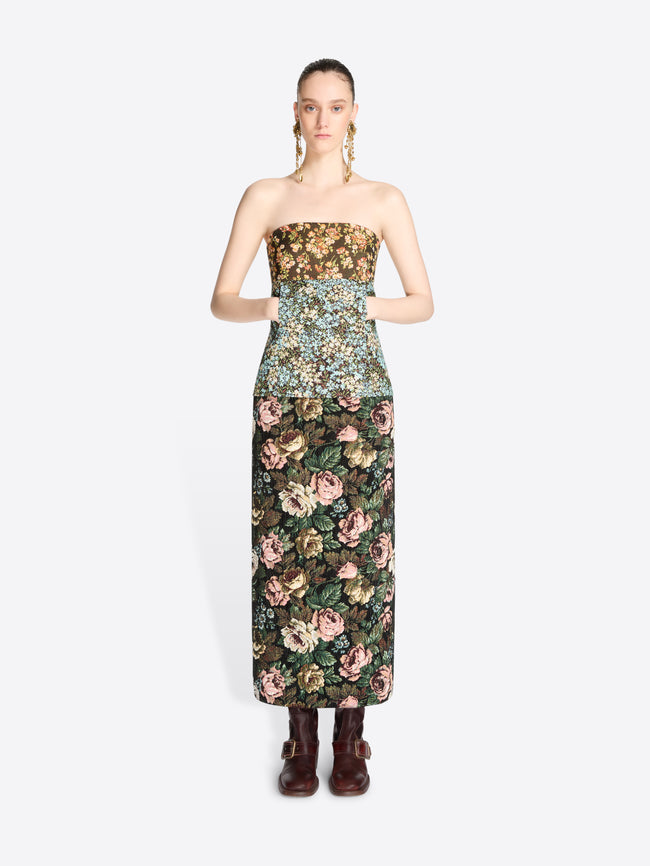 A model wearing a strapless top with a dense floral pattern and matching skirt, paired with dark brown boots against a light gray background.