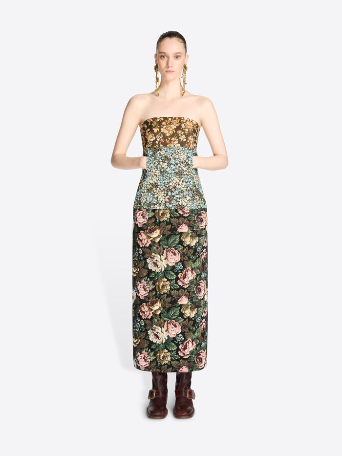 A model wearing a strapless top with a dense floral pattern and matching skirt, paired with dark brown boots against a light gray background.