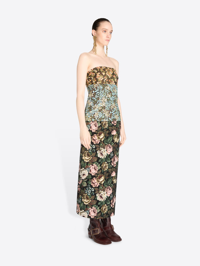 A model wearing a strapless top with a dense floral pattern and matching skirt, paired with dark brown boots against a light gray background.