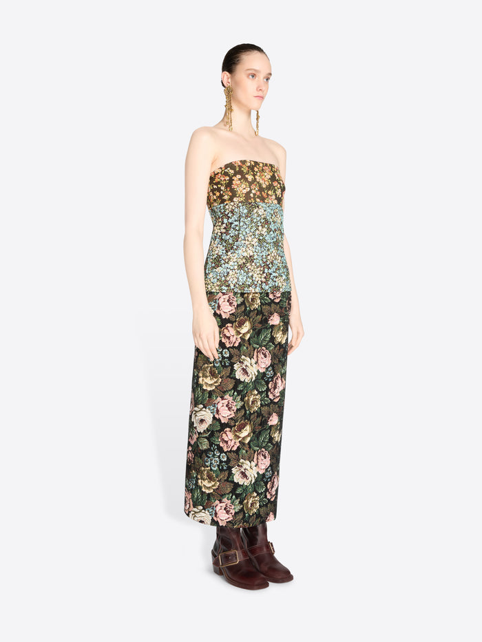A model wearing a strapless top with a dense floral pattern and matching skirt, paired with dark brown boots against a light gray background.