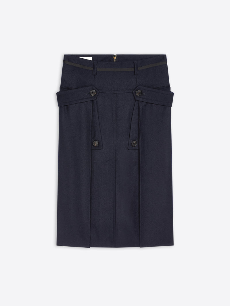 A dark navy blue skirt with structured waist details, buttoned flap pockets, and pleated front panels, shown flat against a light gray background.