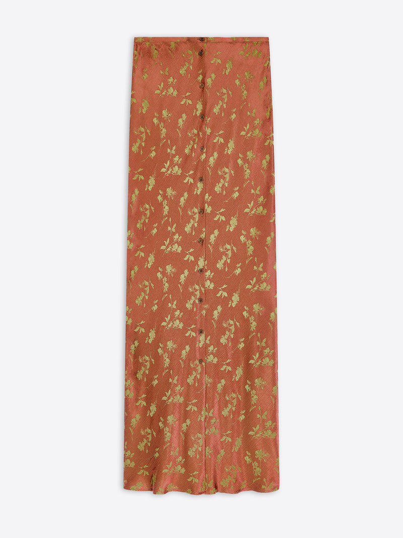 A rust-orange maxi skirt with a gold floral and leafy pattern, shown flat against a light gray background.