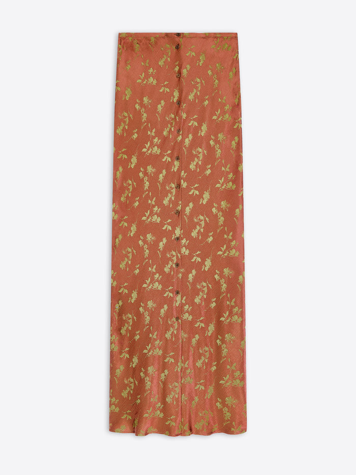 A rust-orange maxi skirt with a gold floral and leafy pattern, shown flat against a light gray background.