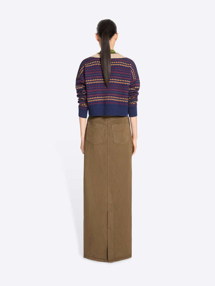 Back view of a model standing against a light gray background wearing a long brown skirt, paired with a patterned knit sweater.