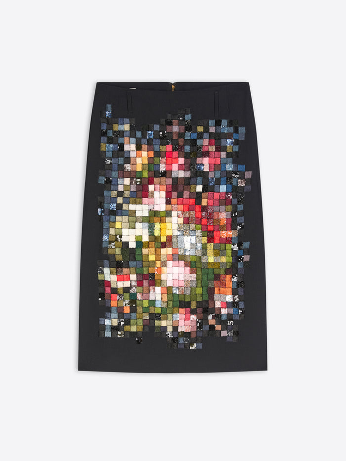 A black pencil skirt featuring a large, colorful pixelated mosaic print of a floral bouquet on the front, displayed flat against a light gray background.