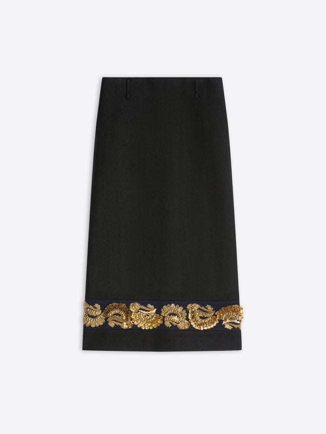 A long black skirt featuring ornate gold embroidery near the hem on a light gray background.