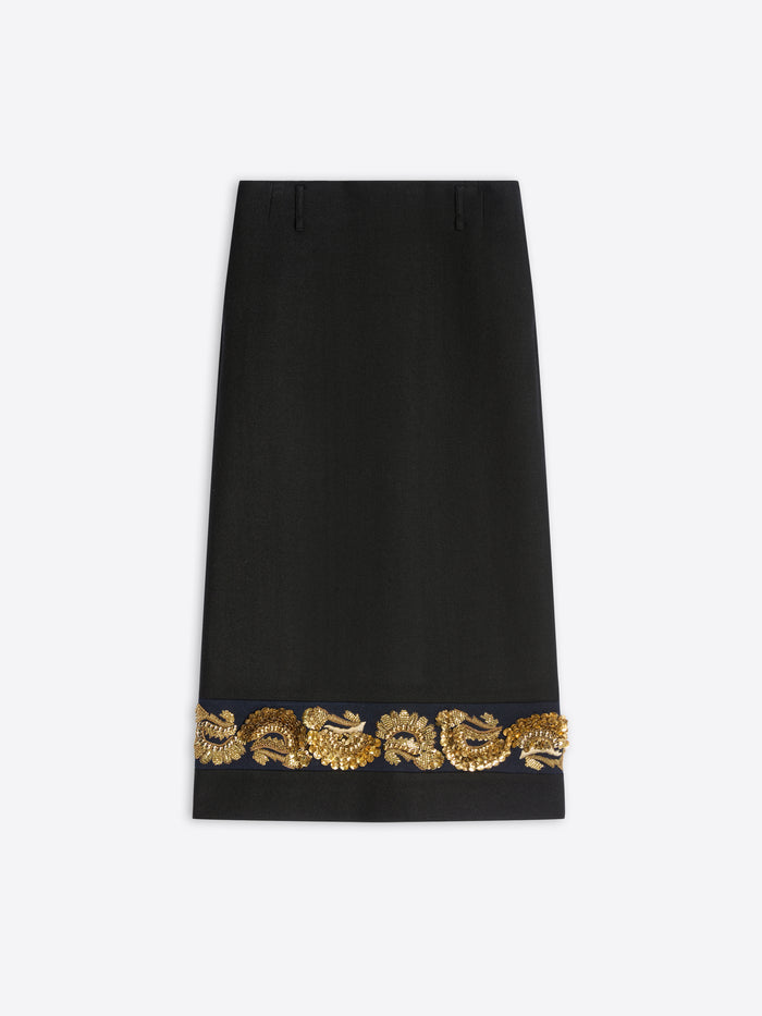 A long black skirt featuring ornate gold embroidery near the hem on a light gray background.