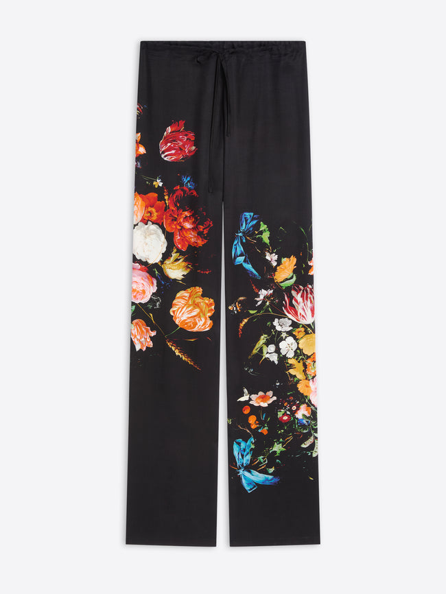 Black wide-leg pants featuring a vibrant, multicolor floral and butterfly print down the front of each leg, displayed flat against a light gray background.