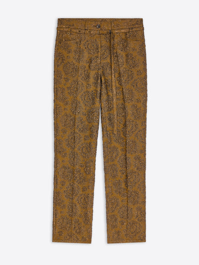 A pair of slim-fit trousers in a textured mustard-brown fabric with an all-over brown paisley pattern, shown flat against a light gray background.
