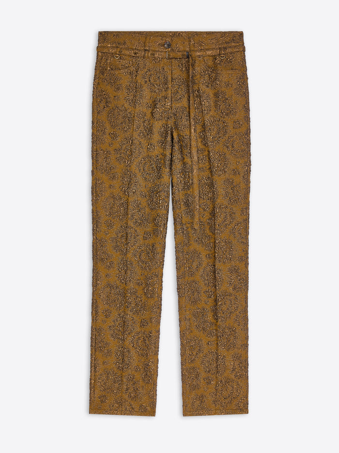 A pair of slim-fit trousers in a textured mustard-brown fabric with an all-over brown paisley pattern, shown flat against a light gray background.