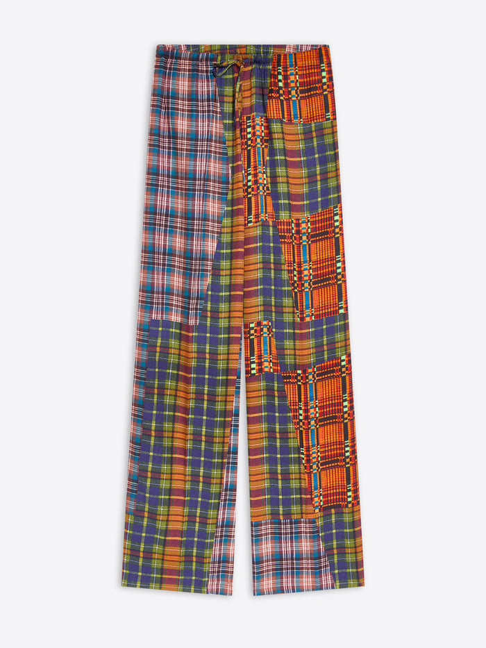 A pair of wide-leg trousers featuring a split design: one leg has a blue, red, and yellow plaid pattern, while the other leg features orange and red geometric tribal-inspired panels with yellow and green accents.