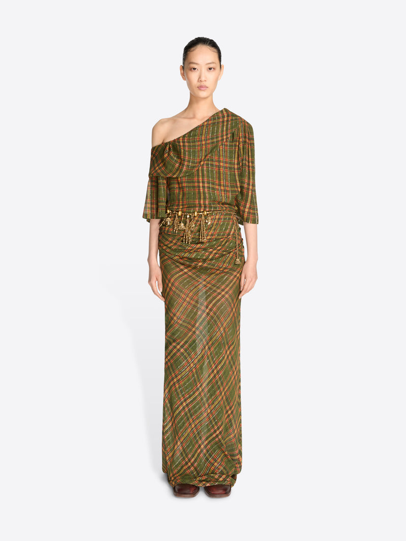 A model wearing a long, one-shoulder dress with a green and brown plaid pattern and gold tassel detailing at the waist, set against a light gray background.