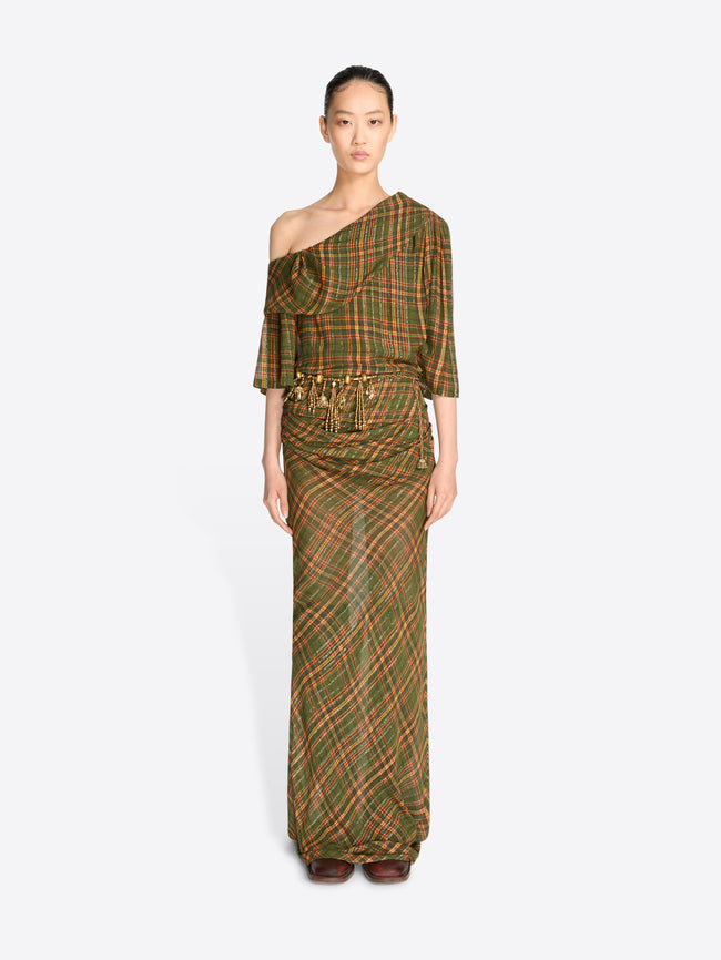 A model wearing a long, one-shoulder dress with a green and brown plaid pattern and gold tassel detailing at the waist, set against a light gray background.