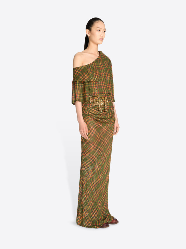 A model wearing a long, one-shoulder dress with a green and brown plaid pattern and gold tassel detailing at the waist, set against a light gray background.